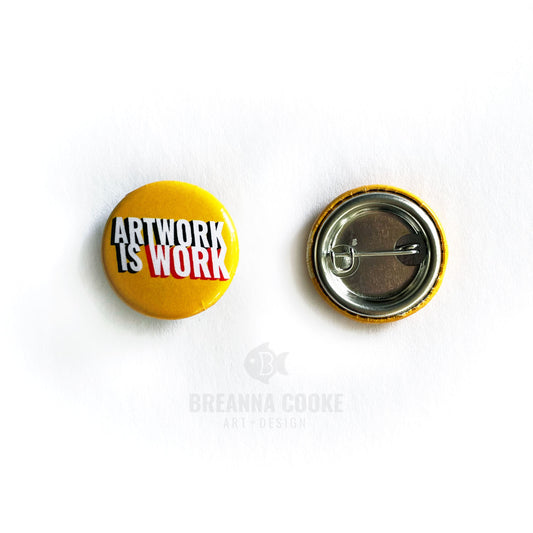 Pin-back button with text "Artwork is work" on yellow background.