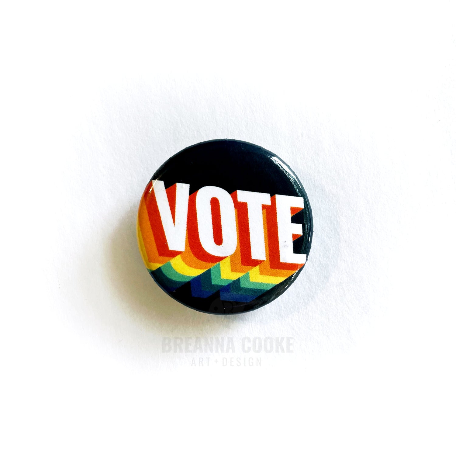 VOTE pin-back button with retro rainbow colors.